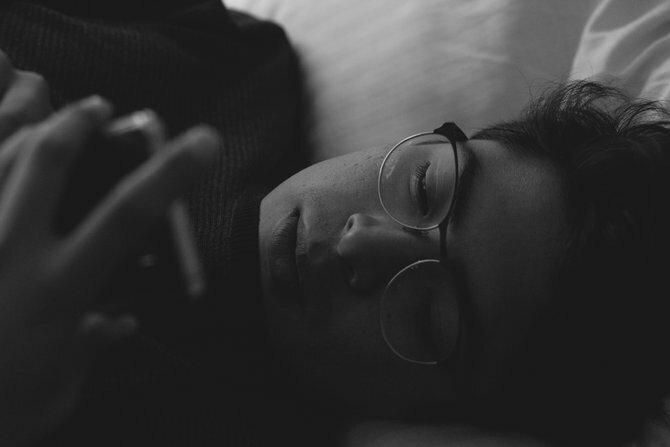 Pessoa olhando para um smartphone na cama
