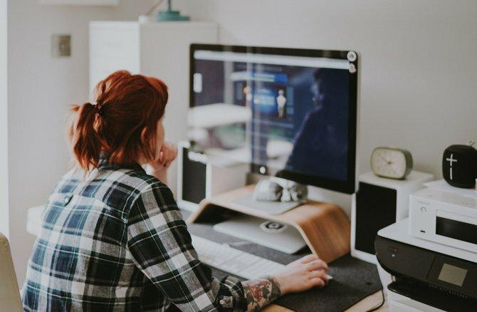 Uma mulher sentada na frente de um monitor de computador