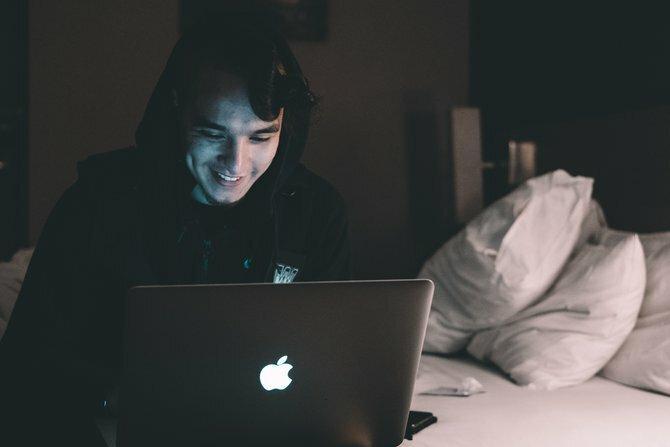 Pessoa usando um laptop à noite, sentada em uma cama