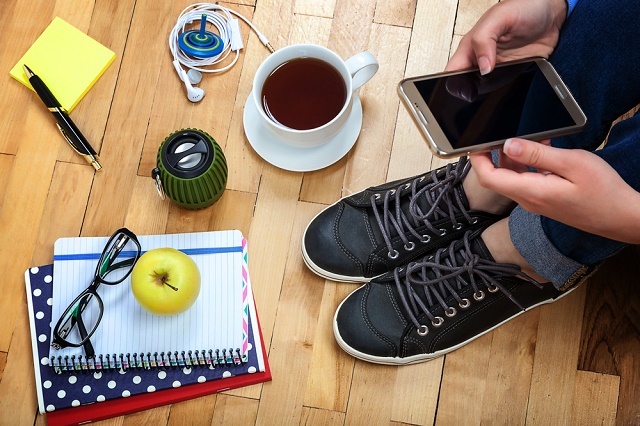 Pessoa com smartphone, xícara de café, notebook etc.