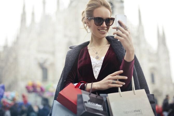 Mulher com sacos de compras, olhando para o telefone