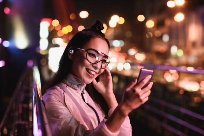 feliz menina asiática com vídeo chat usando o smartphone e fones de ouvido