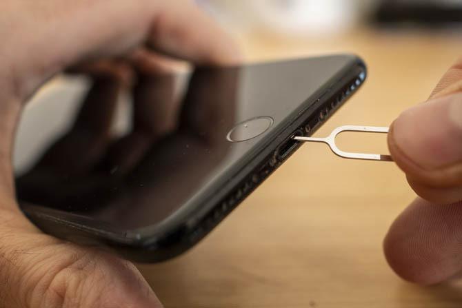 Limpando uma porta de carregamento do iPhone com a chave SIM