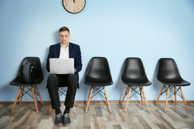 Homem trabalhando no laptop sob relógio